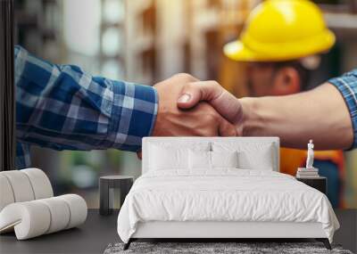 Close-up of a firm handshake between two construction workers at a building site, representing a professional agreement. Wall mural