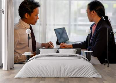 Two people are sitting at a table with papers and a calculator Wall mural