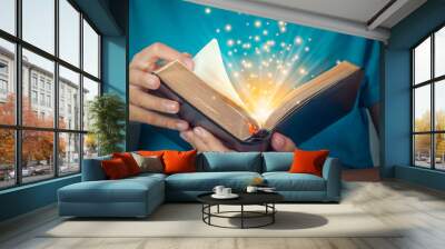 Hand of child opening the gold edge magic book with mystic bright spark light on dark background. Fantasy and discovery magic concept. Wall mural