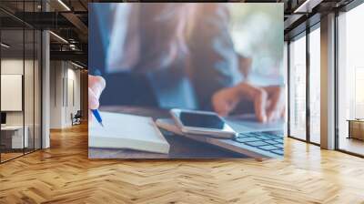 Business woman hand  writing on a notepad with a pen and using laptop in the office.Web banner. Wall mural