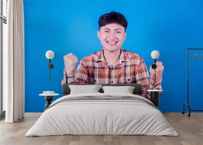 Asian man in Wear a striped shirt smiling on blue background, Joyful expressing celebrating good news victory winning success Wall mural