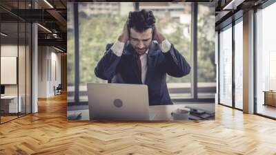 Stressed business man  with hand on head in his office Wall mural