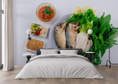 Fried two short bodied mackerel fishes and vegetable on white plate on white table Wall mural