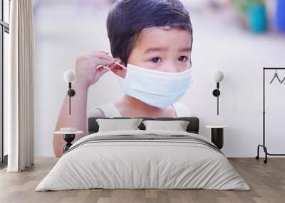 Portrait of cute little Asian 2 -3 years old toddler baby boy so sad face. Child wearing protective medical mask. Virus or PM 2.5 concept.  Wall mural