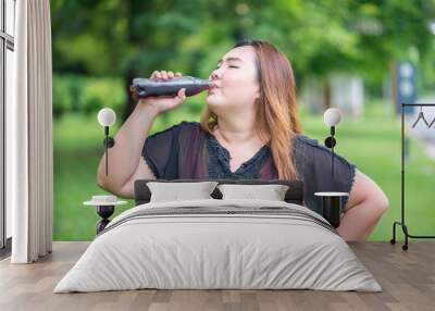 Fat woman drink cola in garden Wall mural