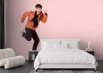 Happy handsome Asian man in fashionable clothing and jumping doing winner gesture isolated on pink background with clipping path. Wall mural