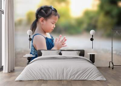 A cute little Asian girl prayed to God in the morning. The concept of prayer for faith, spirit, and religion Wall mural