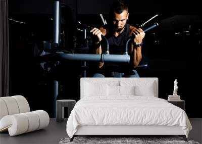 Closeup of a muscular young man lifting weights on dark backgrou Wall mural