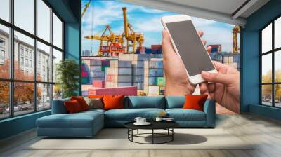 Businesswoman holding smartphone with blurred cargo ship's marine background Wall mural