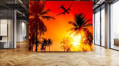 Coconut palms tree and airplane on red and yellow sky background Wall mural