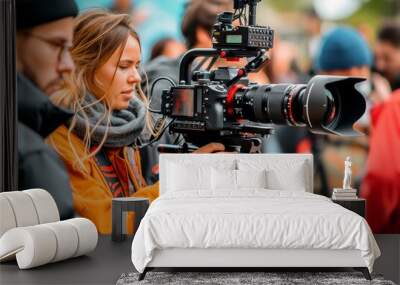 A professional female filmmaker operating a camera with a male assistant on a bustling film set. Wall mural