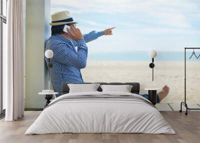 Back side view of man pointing finger talking on smartphone . beach terrace sunny day outside background Wall mural