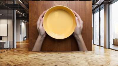 a female hands hold a empty(blank) white dish(plate) on the wood Wall mural