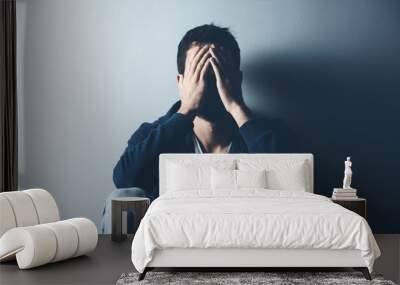 sad man sitting on ground on dark background Wall mural