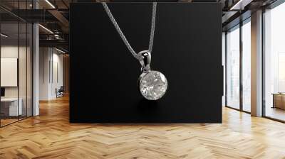 A silver necklace with a diamond pendant. The pendant is a large, clear diamond. The necklace is on a black background Wall mural