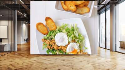 Classic French salad, great salad Lyonnaise. Dish with green leaves of lettuce, Dijon mustard sauce with pieces of fried bacon, grilled French bread, toasts and 2 poached aggs on the top. Wall mural