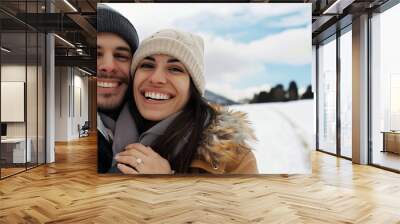 A happy young couple laughing and hugging in the winter snow Wall mural