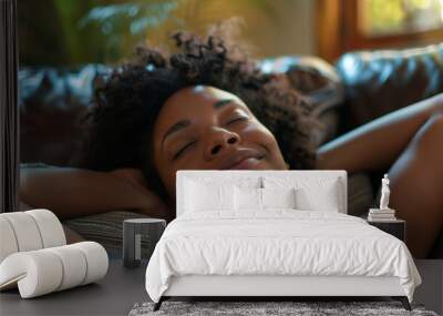 A young happy black woman lying back on a sofa relaxing Wall mural