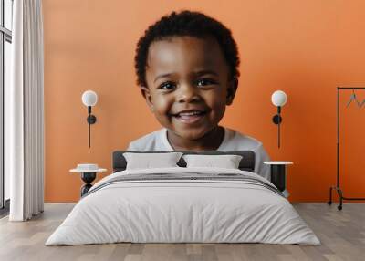 african toddler boy orange background wearing plain white tshirt smiling happy portrait Wall mural