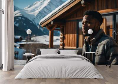 Content Black male in cozy chalet with snowy mountains background Wall mural