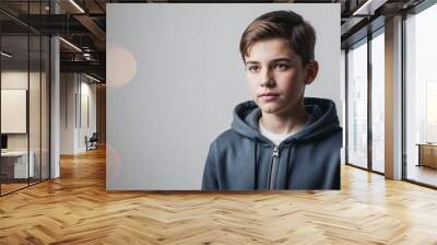 Focused Caucasian teenage boy with short brown hair wearing hoodie on plain white background Wall mural