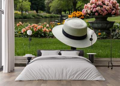 Hat resting on a bench in a public garden with blooming flowers Wall mural