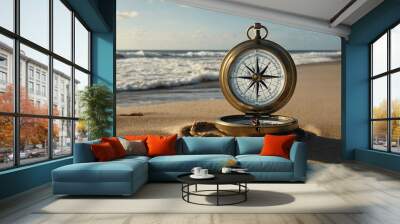 Map and compass on a sandy beach with waves crashing nearby Wall mural