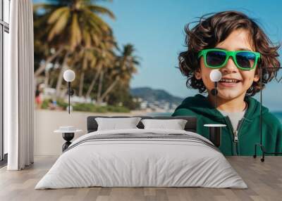 Playful Latin Hispanic Kid with Wavy Hair in Green Hoodie and Sunglasses at a Sunny Beach Wall mural