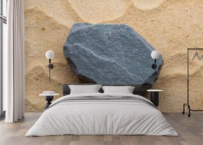 Rough gray basalt stone placed on a sandy colored background showing its raw edges Wall mural