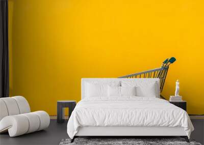 An empty shopping cart set against a vibrant yellow-orange background with ample negative space for text Wall mural