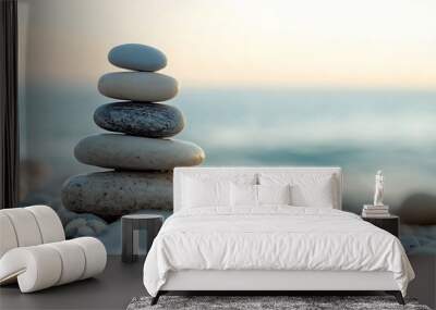 Stack of white and grey stones balancing on pebble beach at sunset Wall mural