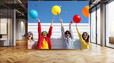 A vibrant beach party with joyous students celebrating under the sun, holding colorful balloons against a clear sky. Wall mural