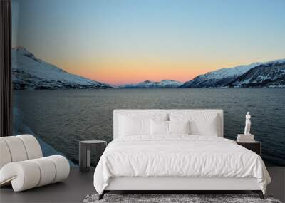 Vibrant colours on dawn sky over cold arctic fjord water and majestic snowy mountain range Wall mural