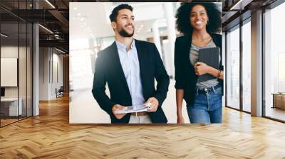 The business world is in constant motion. Shot of a young businessman and businesswoman having a conversation while walking through a modern office. Wall mural