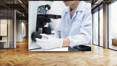 Close up scientist hand adjust the microscopy for scientist diagnosis bacteria from body fluid.Medical tool concept.Selective focus. Wall mural