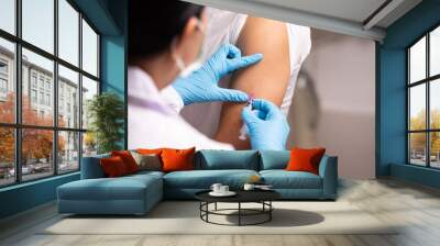 Doctor hand in blue gloves holding influenza vaccine for prevention human.Nurse holding syringe make injection in shoulder of patient in hospital.Covid-19 or coronavirus vaccine. Wall mural