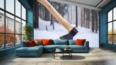 Axe stuck in a snowy log  in a tranquil winter forest Wall mural