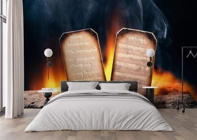 Old religious papers  burning on a rock with fire on dark background. Copy space. Wall mural