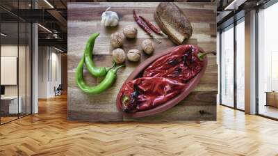 Roasted red peppers in a ceramic pot on a wooden table, accompanied by two slices of traditional natural wheat bread, red and green peppers, a head of garlic. Healthy eating food low carb diet Wall mural