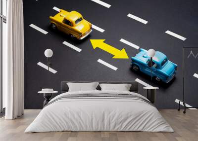 Two toy cars on the road one after another. Wall mural