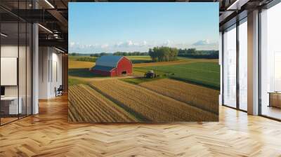 Aerial view of a scenic rural farm with a red barn and a vast landscape of green and brown fields under a clear blue sky. Wall mural