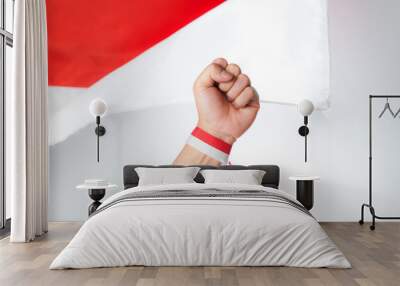 Human hand clenched into a fist with red and white ribbon with Indonesian flag background Wall mural