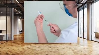 closeup to latin woman doctor taking syringe and glass container with medicine to inject it as pandemic vaccine Wall mural