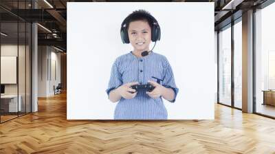 Adorable gamer smiling happily and confidently. Standing with smile on face raising hands celebrating victory playing video game using gamepad and headphones on isolated white background Wall mural