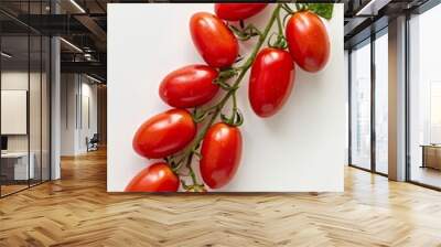 A cluster of red ripe tomatoes on a vine with green leaves against a white background Wall mural