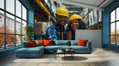 Two warehouse workers in hard hats look at a laptop computer Wall mural