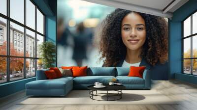 A young woman with curly hair smiles confidently in a busy business environment, representing professionalism, leadership, and career success.

 Wall mural