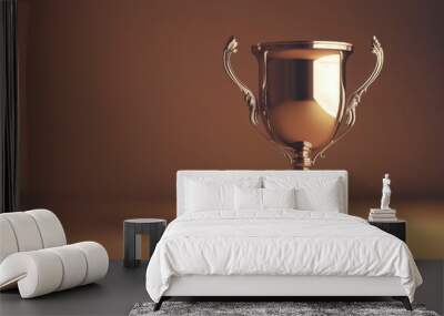 A gleaming golden trophy with two handles stands on a brown surface, signifying achievement and victory. Wall mural