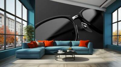 Close-up of stylish black sunglasses on a dark background, showcasing modern design and sleek frame details. Wall mural