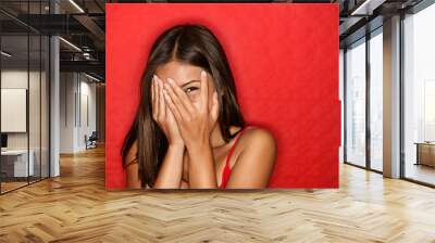 Playful shy woman hiding face laughing Wall mural